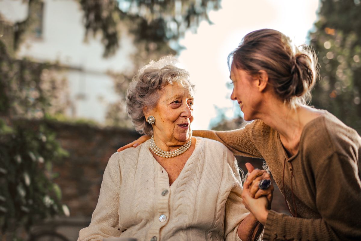 An older woman laughing with a companion during a home visit