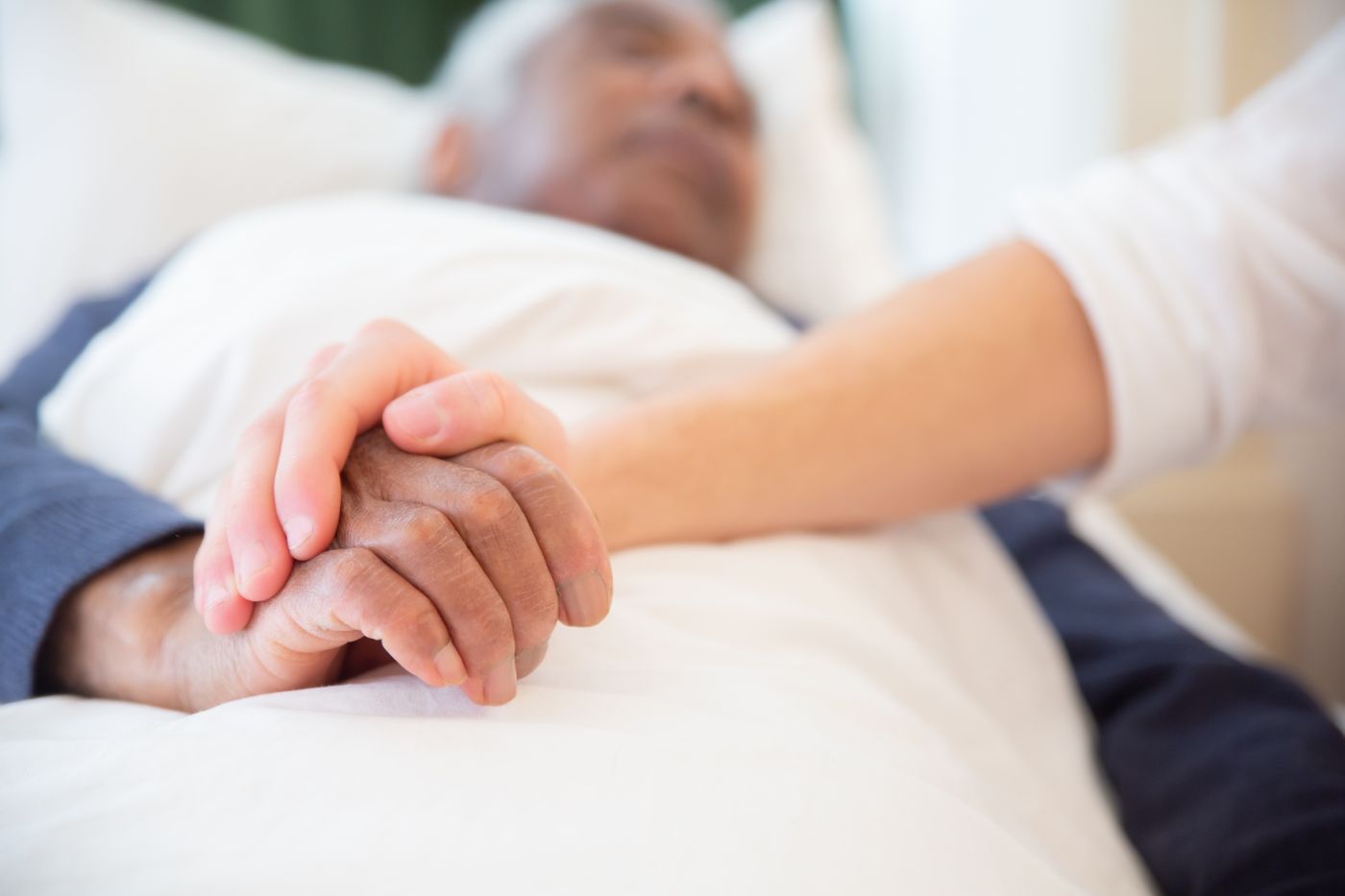 A caregiver holding an older adult’s hand